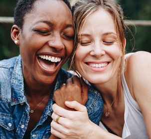 Patient in Natick with dental implants smiling with a friend