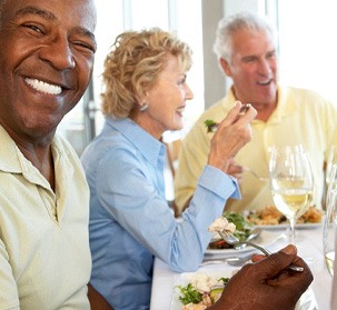 Patient in Natick with dental implants dining with friends