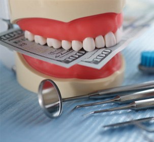 An artificial jaw mockup with money and dental instrument on table