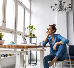 a woman lounging at a table and looking out a window