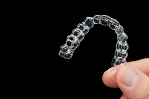 Close-up of hand holding Invisalign aligner