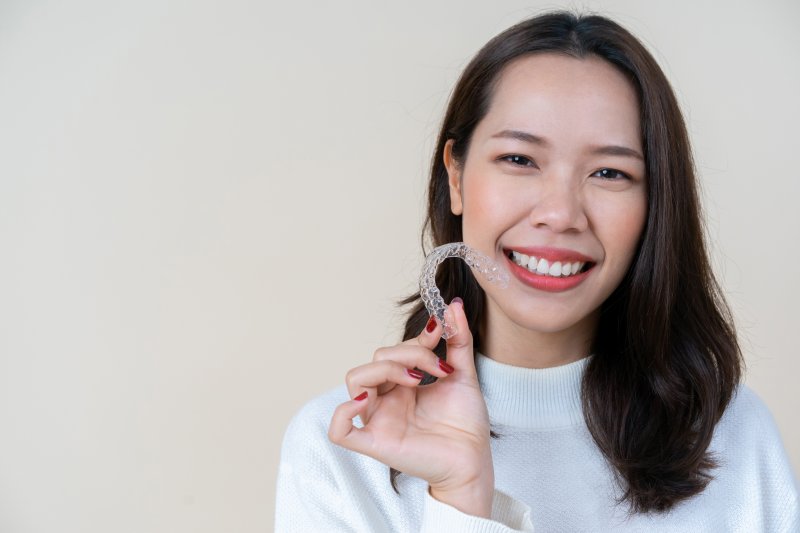 smiling person holding an Invisalign aligner tray